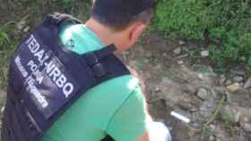 Un mosso d'esquadra junto a una granada hallada en unos terrenos / MOSSOS D'ESQUADRA