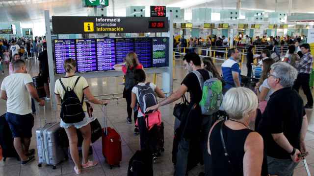 Un grupo de pasajeros ante una pantalla del aeropuerto de Barcelona, este viernes / EFE