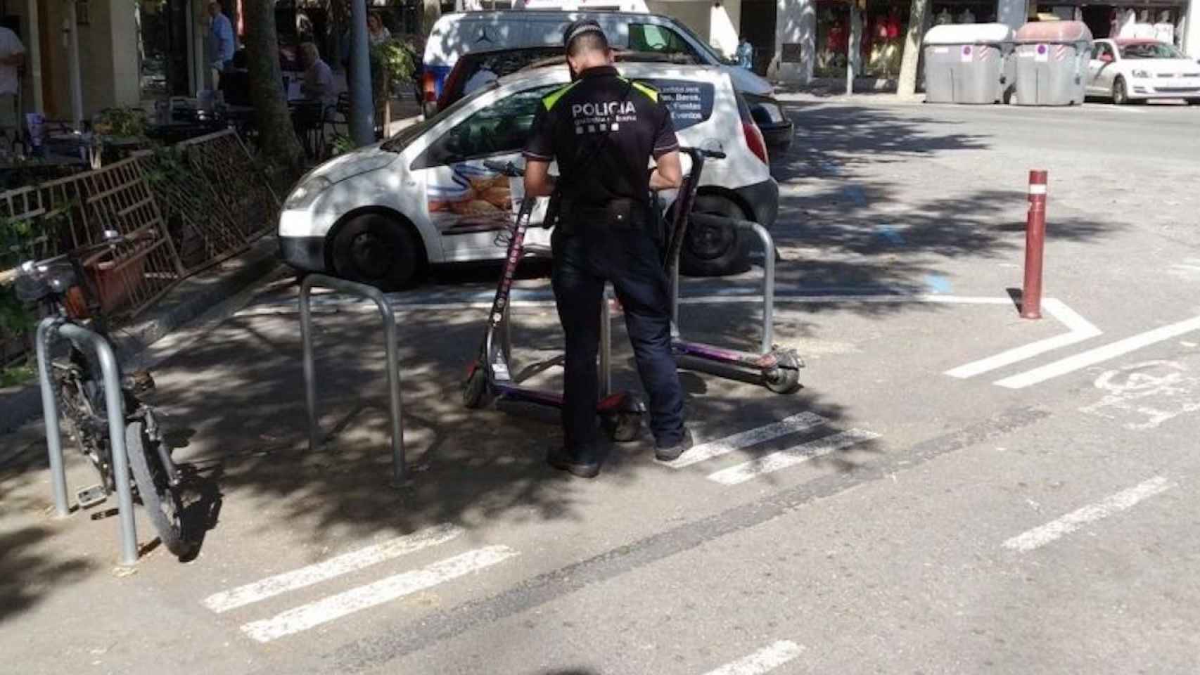 Un guardia urbano multa un patinete mal estacionado en Barcelona / JORDI SUBIRANA