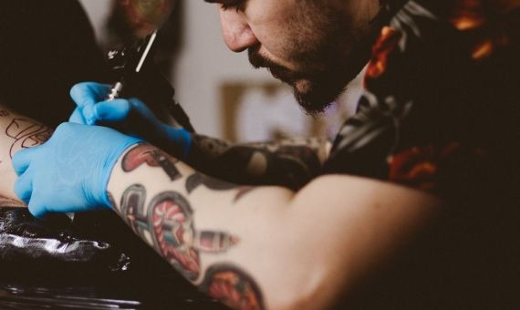 Imagen de un tatuador concentrado con un diseño 