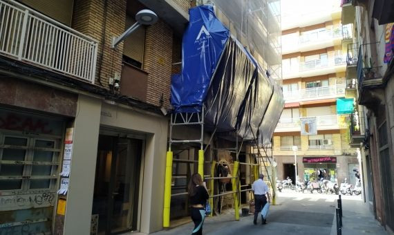 La fachada del edificio afectado en Gràcia recubierta con lonas y andamios / P.B.