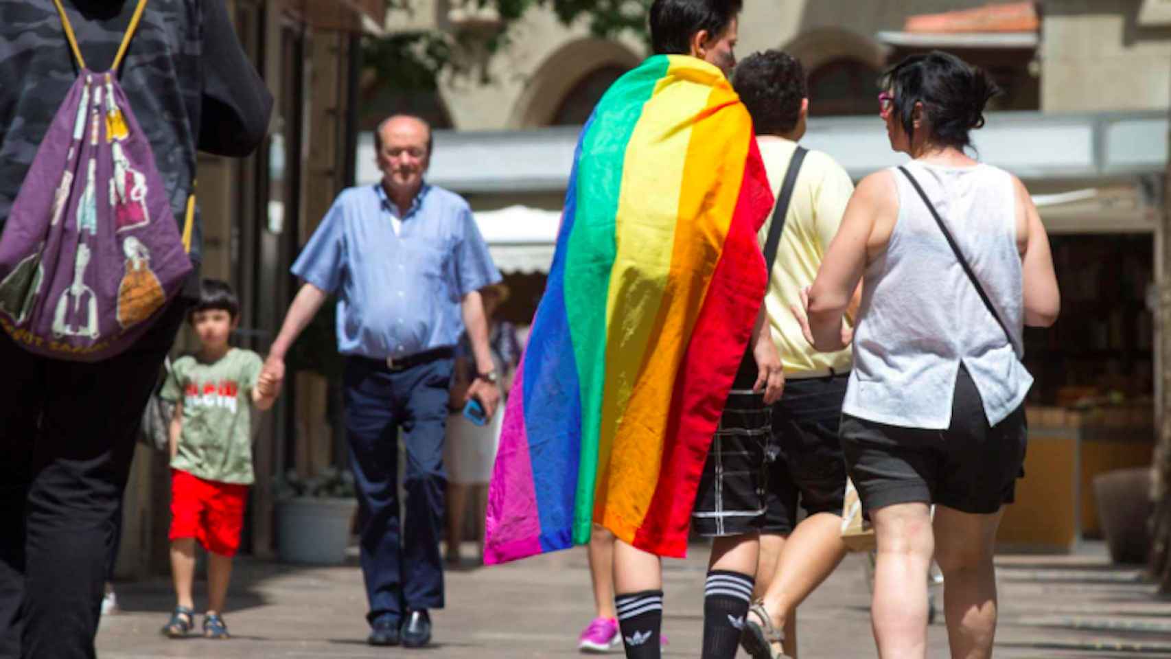 Una pareja camina por la calle con la bandera arcoiris, emblema del colectivo LGTBI / EFE