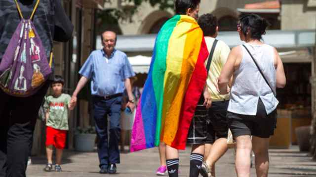 Una pareja camina por la calle con la bandera arcoiris, emblema del colectivo LGTBI / EFE