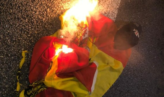 La bandera franquista con el águila de San Juan quemando en el suelo / MA