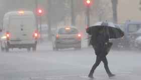 Una persona cruza una calle durante un día de lluvia / EFE