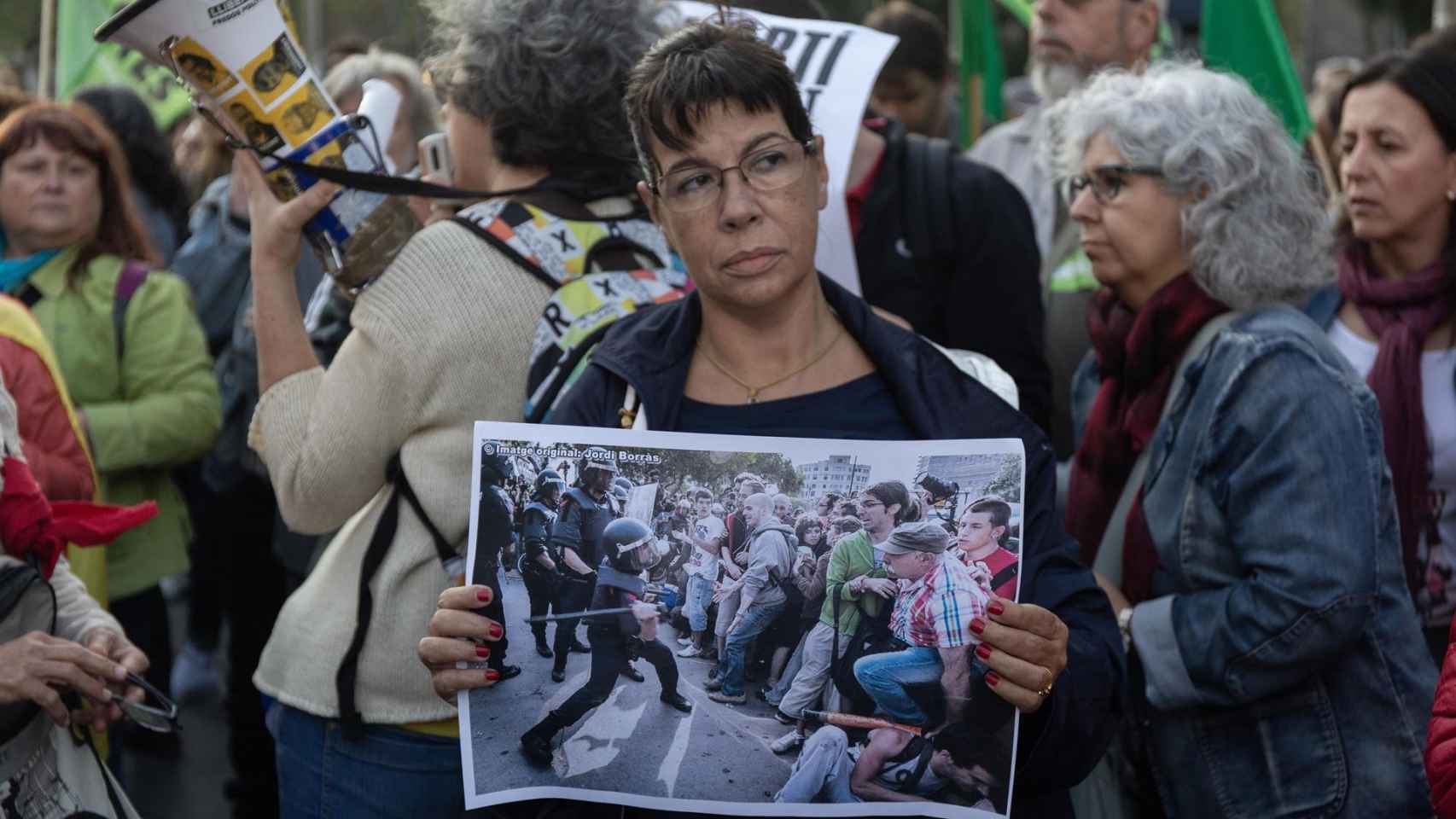 Una mujer exhibe una imagen de las cargas en la manifestación que ha reunido a 4.000 personas  / EUROPA PRESS