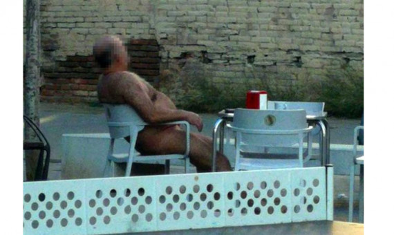 Un hombre se toma un café en una terraza completamente desnudo