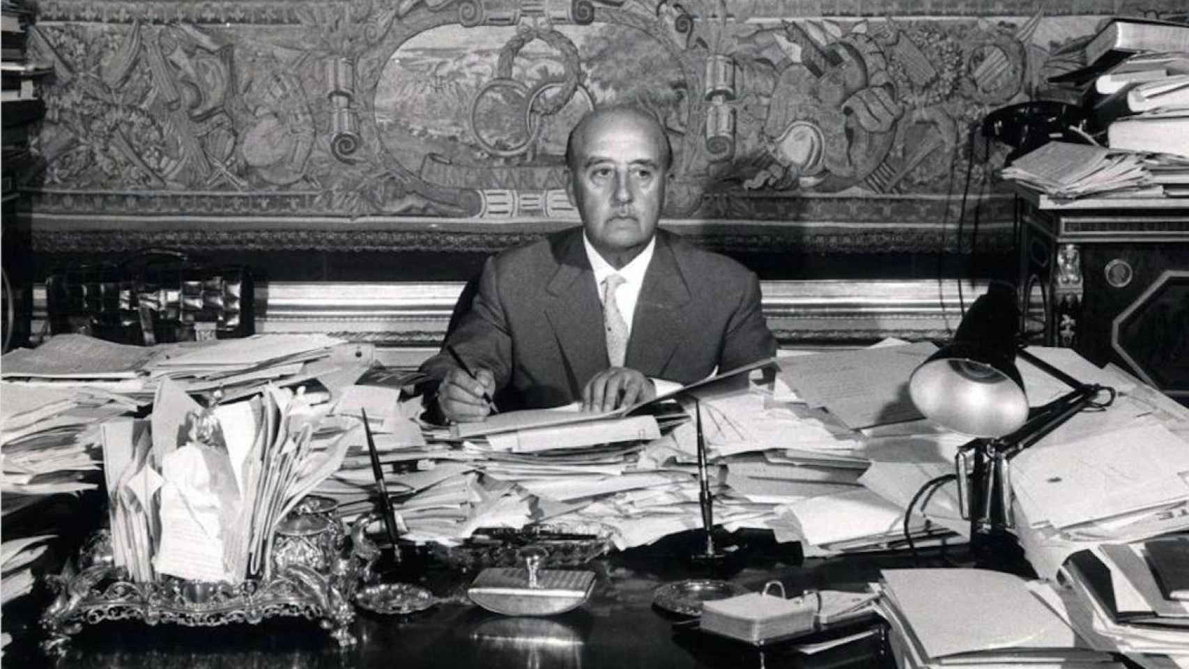 Francisco Franco, sentado ante la mesa de su despacho del palacio de El Pardo, habitualmente atestada de papeles.  / EFE