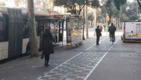 Un ciclista esquiva a un peatón junto a la parada de bus de Diagonal con Girona / JORDI SUBIRANA