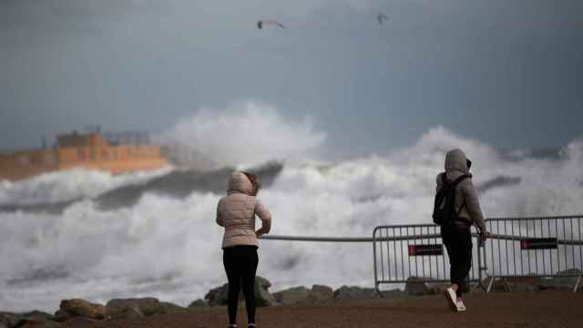 Dos personas observando el oleaje en la playa de la Barceloneta