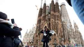 Turistas se fotografían ante la Sagrada Familia en un día de fuerte viento