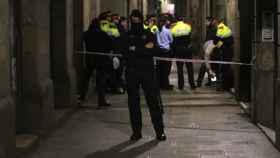 Un policía junto a un conjunto de agentes en un callejón de Barcelona