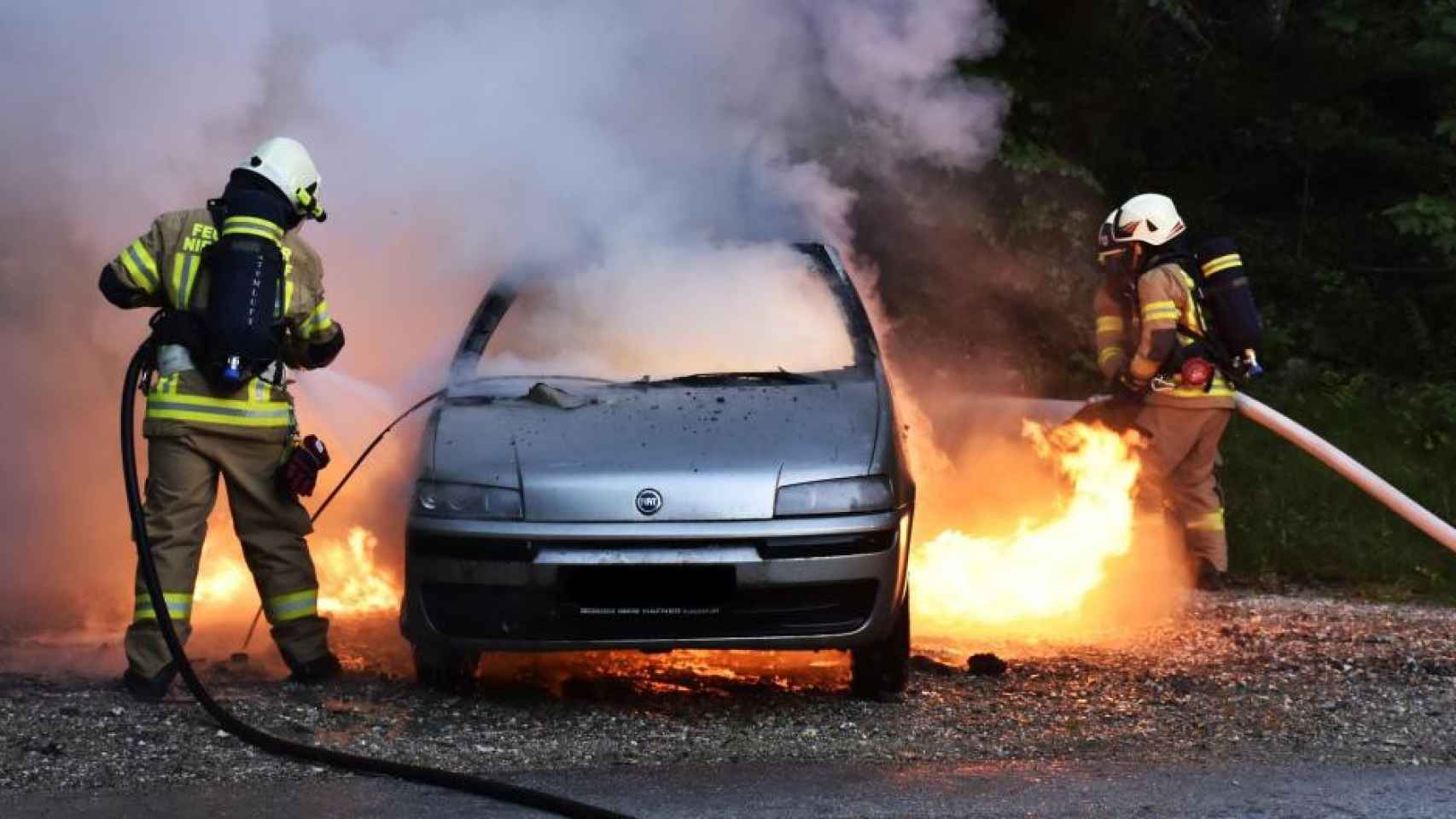 Foto de un coche incendiado, con los bomberos aplicando las labores de extinción / PIXABAY