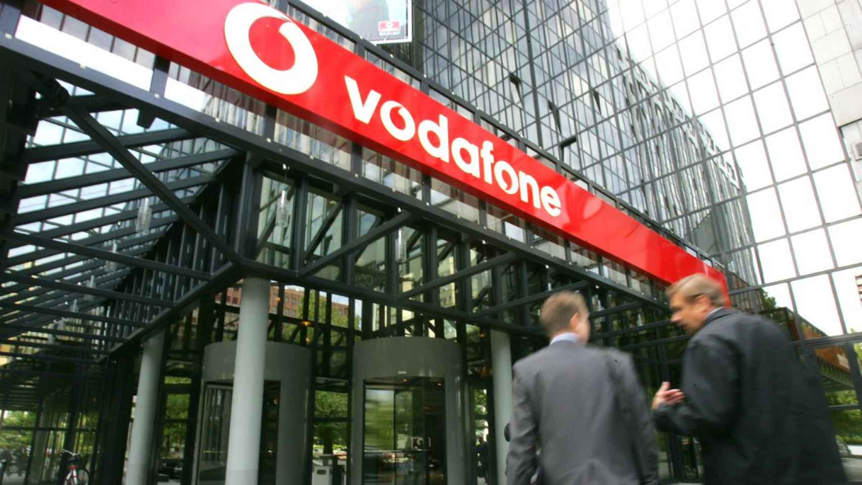 Exterior de las oficinas de Vodafone con dos personas entrando