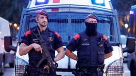 Una pareja de agentes de los Mossos d'Esquadra ante un furgón policial