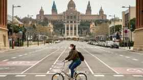 Una ciclista con mascarilla por la avenida Reina Maria Cristina