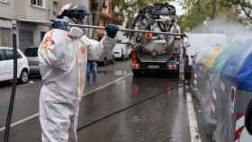 Un trabajador desinfecta los contenedores en Barcelona como medida de protección contra el coronavirus / AJ. DE BCN