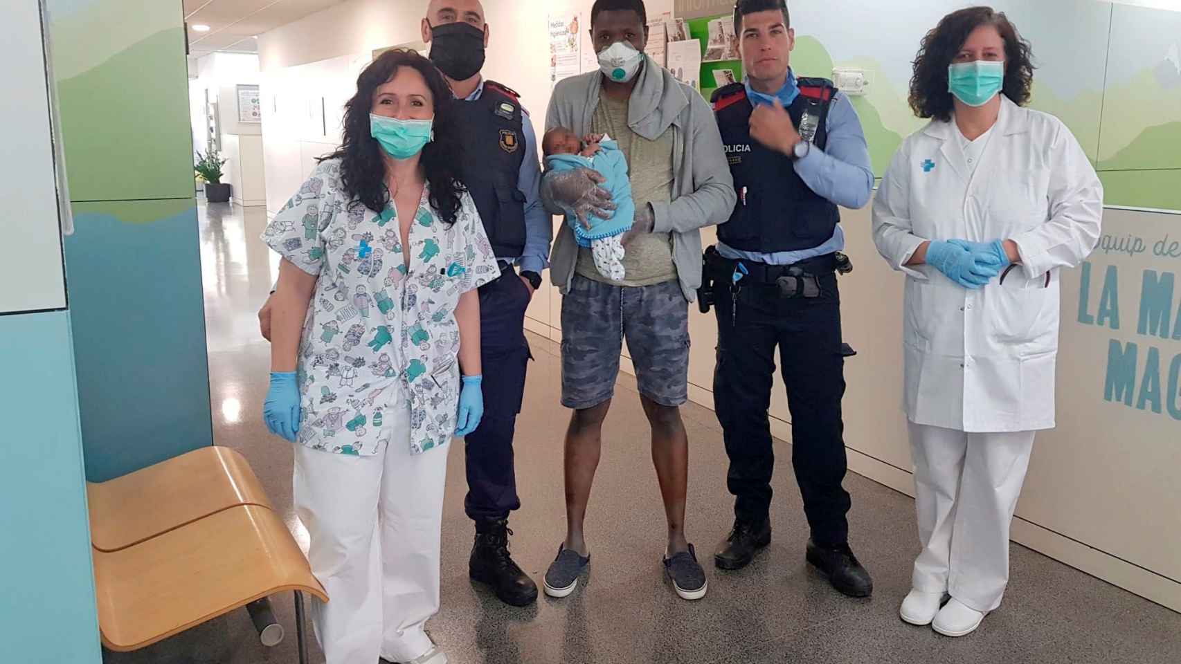 Agentes de los Mossos d'Esquadra posan junto al padre y el bebé en un ambulatorio del barrio de Sants de Barcelona  / EFE