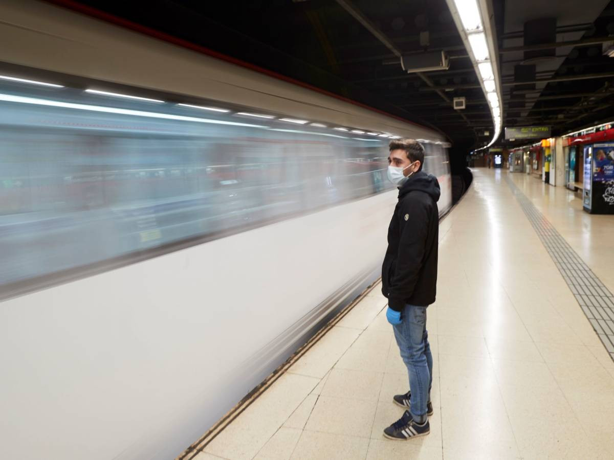 Un usuario del metro, con guantes y mascarilla, espera la llegada de un convoy en la estación de Catalunya