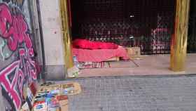 Un indigente, junto a sus libros, duerme en el centro de Barcelona / GUILLEM ANDRÉS