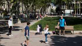 Un adulto y tres niños juegan a pelota en una plaza de Gràcia / EFE