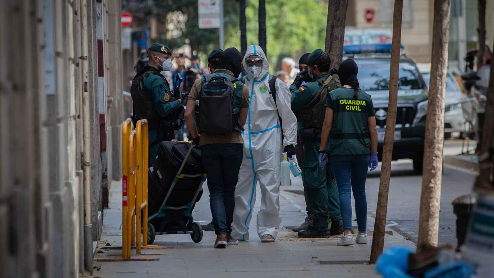Agentes de la Guardia Civil totalmente protegidos salen de un domicilio de la calle de Josep Anselm Clavé en el distrito de Ciutat Vella de Barcelona donde detuvieron al presunto
