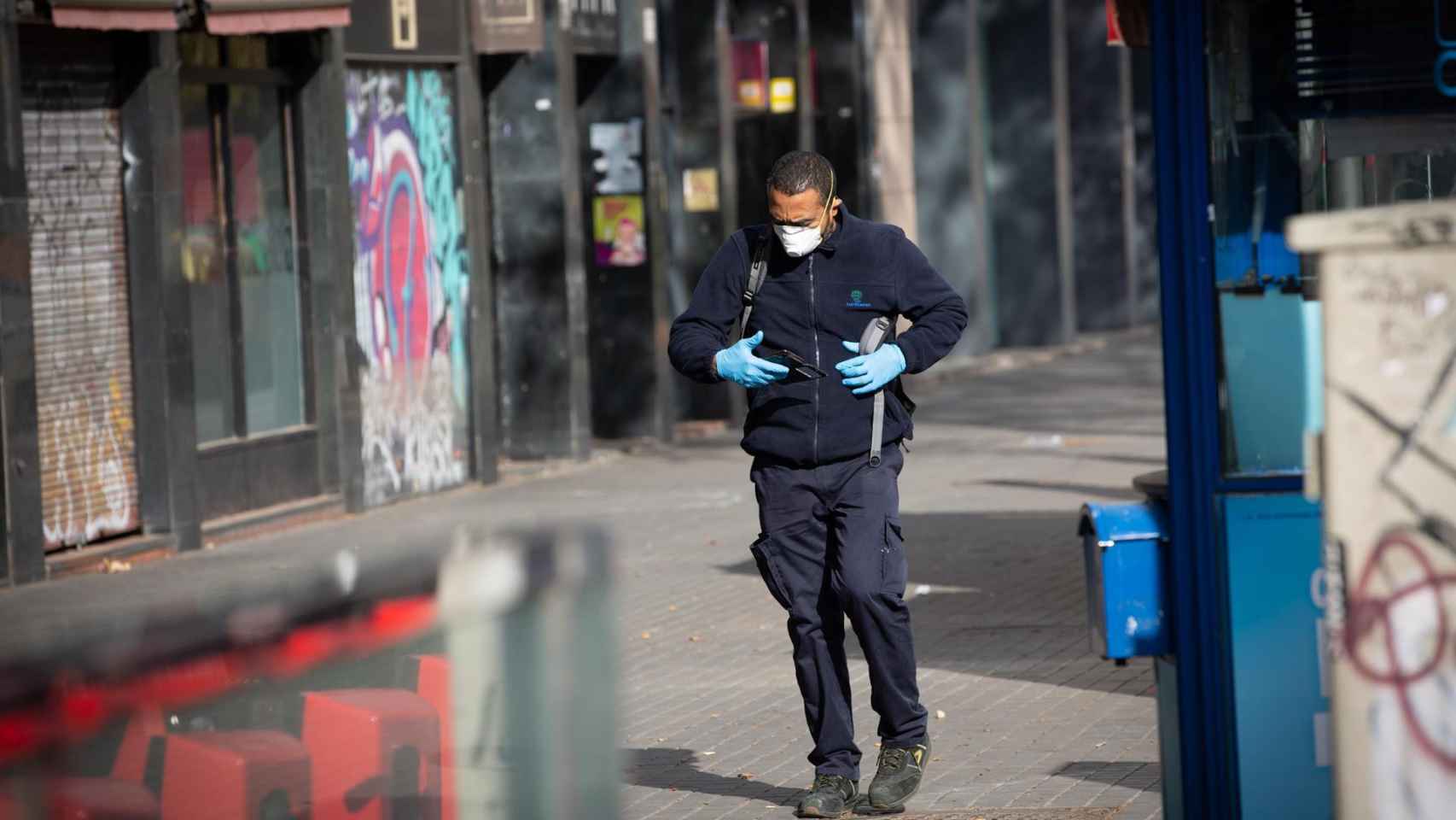Un hombre camina por Barcelona protegido con mascarilla y guantes / EP