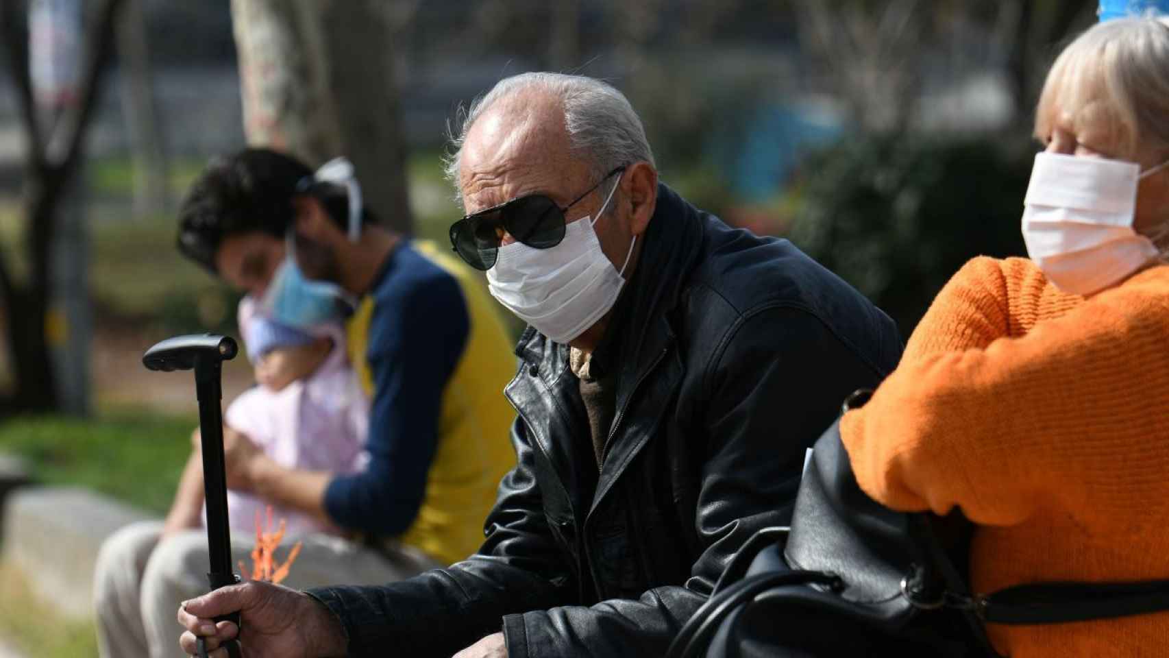 Gente mayor sentada en un banco con mascarilla / REUTERS