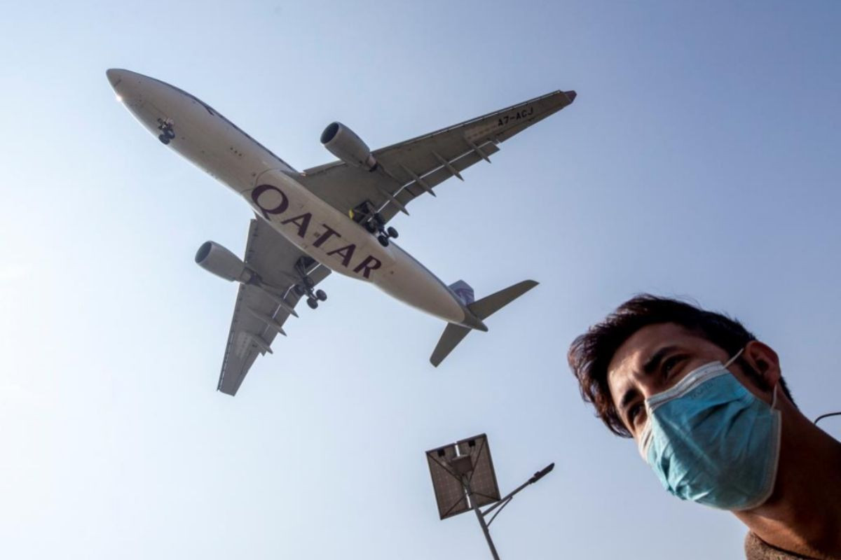 Un hombre con mascarilla camina mientras un avión de Qatar aterriza en el aeropuerto de Katmandú / EFE