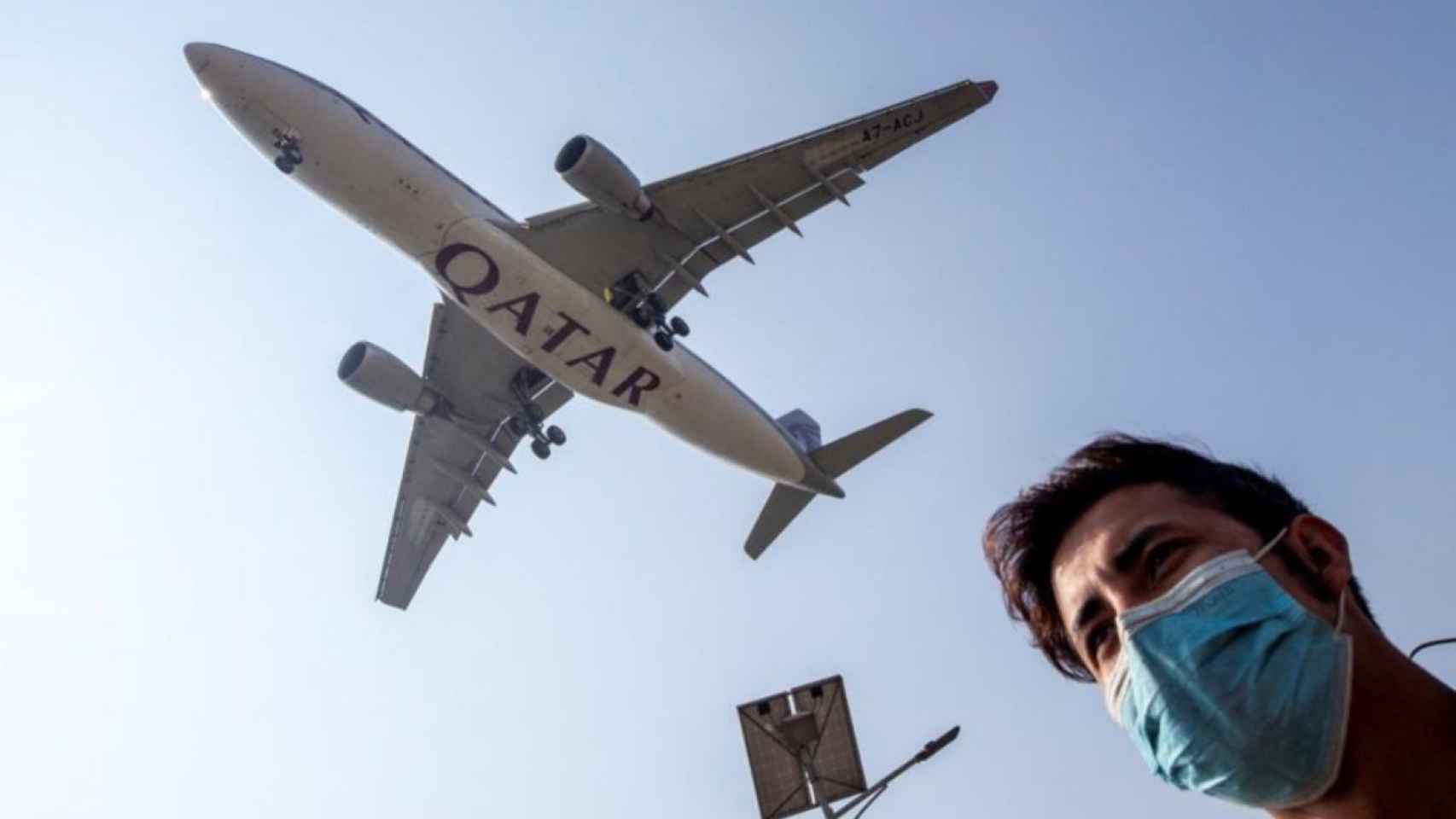 Un hombre con mascarilla camina mientras un avión de Qatar aterriza en el aeropuerto de Katmandú / EFE
