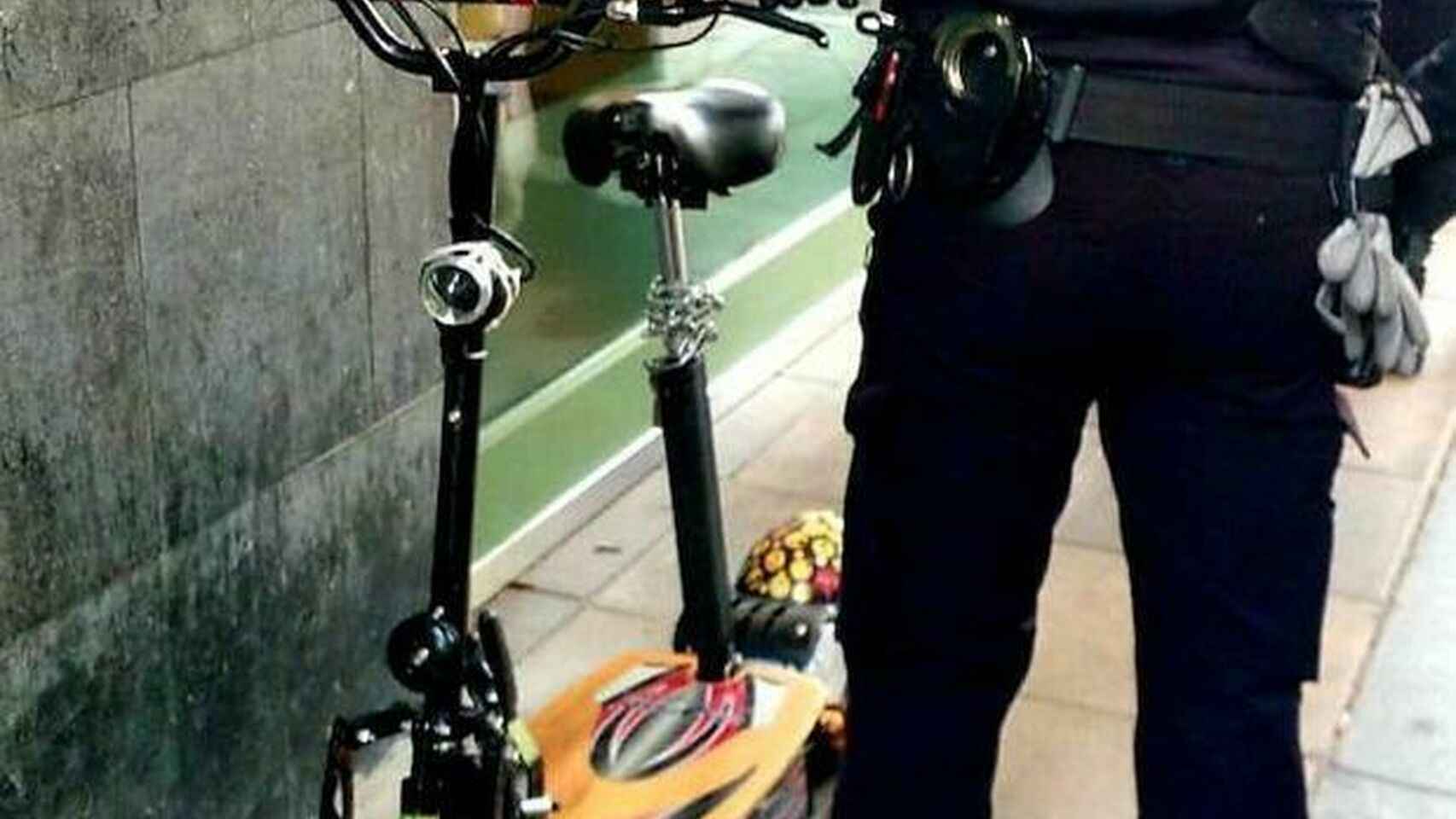 Un agente de la policía con un patinete aparcado