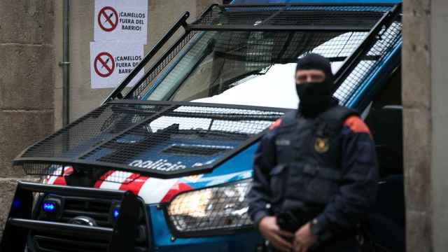 Un agente de Mossos dEsquadra espera en la puerta de un edificio del barrio de “El Raval”, en el distrito de Ciutar Vella de Barcelona, durante un operativo contra el