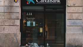 Un sintecho durmiendo en una sede bancaria de 'La Caixa' del barrio Gòtic en funcionamiento / VERÓNICA SÁNCHEZ - @verosan90