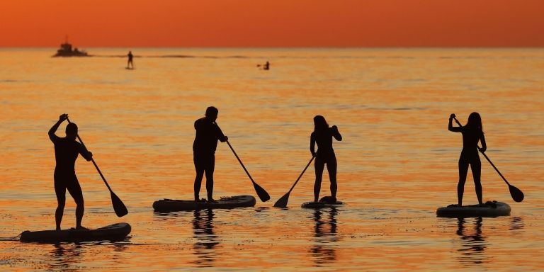 Más personas practicando 'paddle surf' en la playa de la Barceloneta al amanecer / EFE - Andreu Dalmau