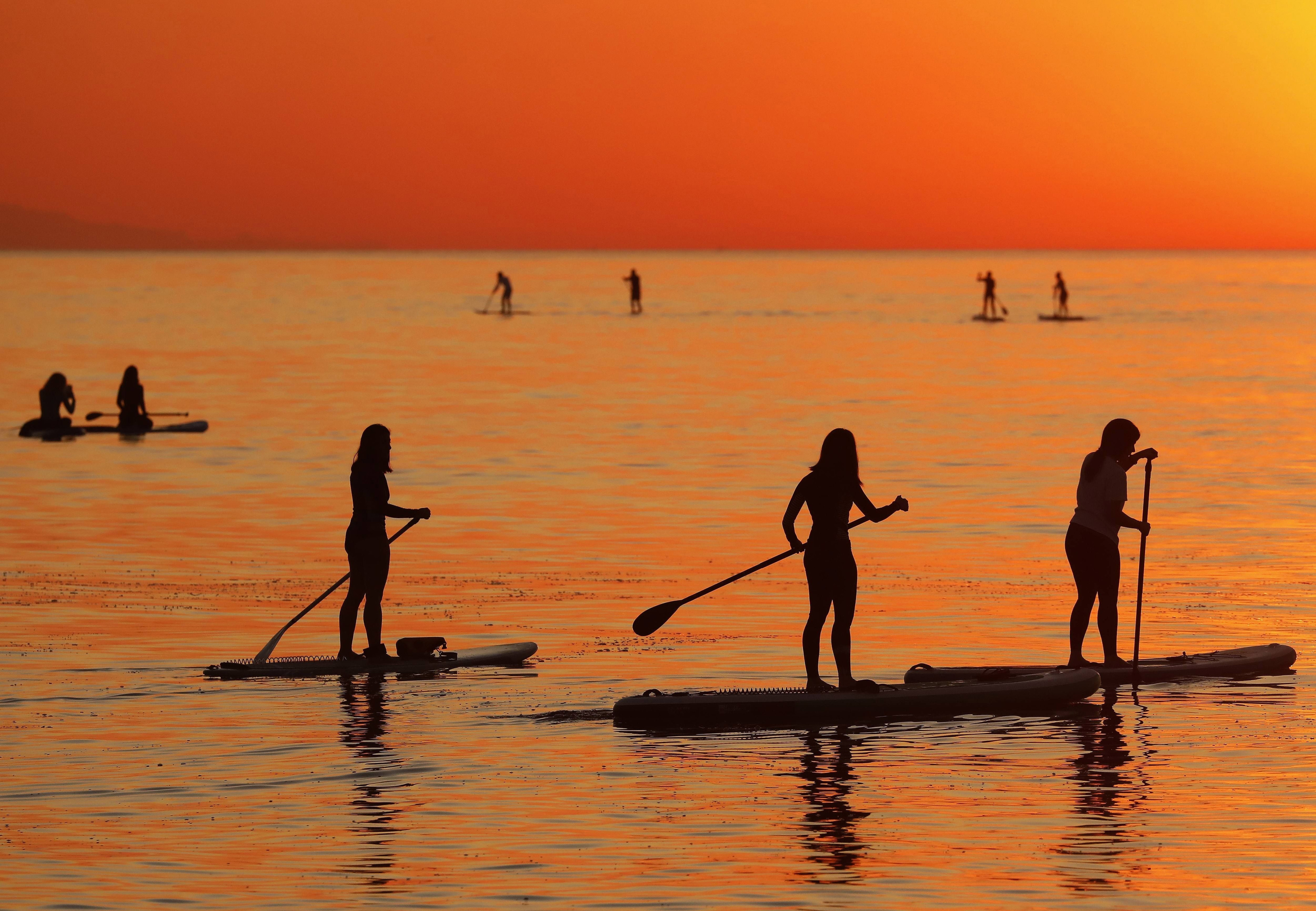 Nueve personas practican 'paddle surf' al amanecer en la playa de la Barceloneta / EFE - Andreu Dalmau