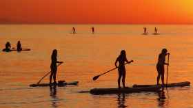 Nueve personas practican 'paddle surf' al amanecer en la playa de la Barceloneta / EFE - Andreu Dalmau