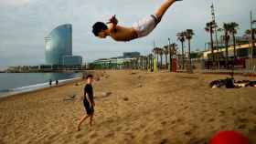 Un saltimbanqui practicando una acrobacia en una playa de la Barceloneta / EFE - Enric Fontcuberta
