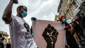 Un hombre protesta contra el racismo con una pancarta, ataviado con su mascarilla / EFE - Enric Fontcuberta