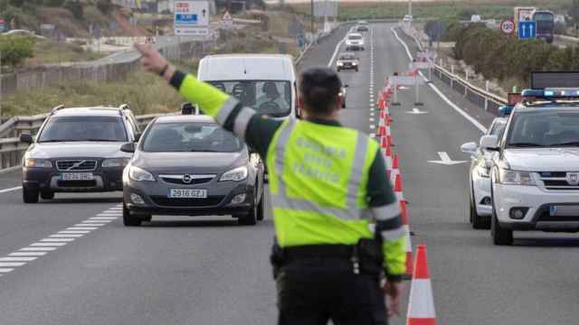 Un policía dirigiendo una decena de coches durante la pandemia / EFE