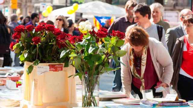 Parada de Sant Jordi con ramos de rosas y libros en la mesa