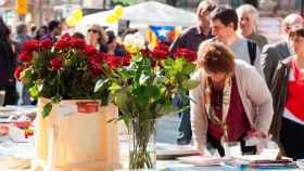 Parada de Sant Jordi con ramos de rosas y libros en la mesa