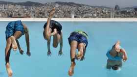 Cuatro jóvenes se tiran de cabeza al verano en las piscinas municipales Sant Jordi / EFE - Andreu Dalmau