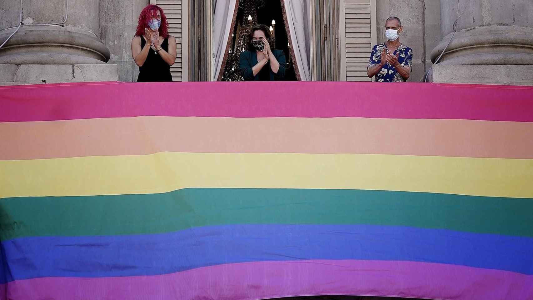 Ada Colau y representantes del colectivo LGTBI colgando la bandera en la fachada del Ayuntamiento de Barcelona / AYUNTAMIENTO DE BARCELONA