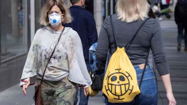 El Govern impone más restricciones en tres municipios barceloneses. En la imagen, una mujer con la cara cubierta con una mascarilla / EFE