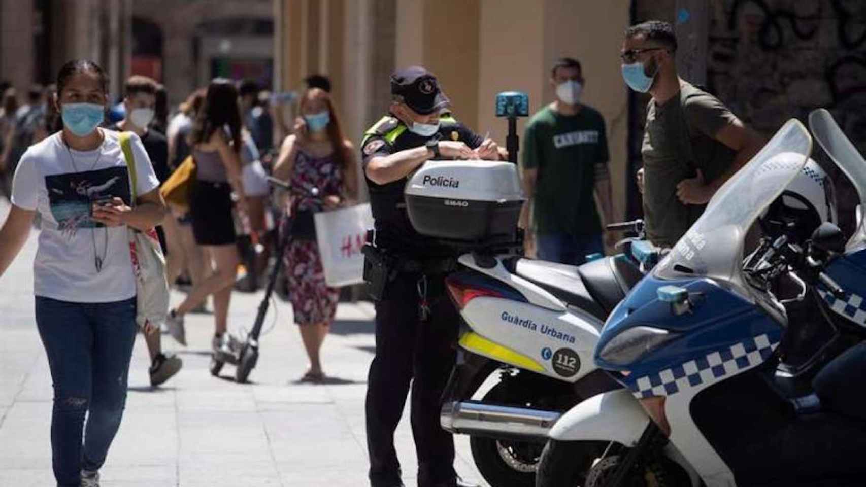 Un policía multa a un ciclista por una infracción cometida y le advierte también de la obligatoriedad de llevar mascarilla en el centro de Barcelona / EFE - MARTA PÉREZ