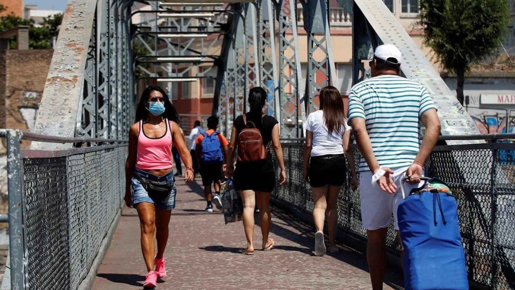 Vecinos cruzan el puente de la Torrassa en L’ Hospitalet de Llobregat, barrio donde hay un nuevo brote de la COVID-19 / EFE - TONI ALBIR