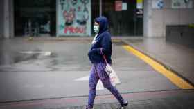 Una mujer camina protegida contra el contagio