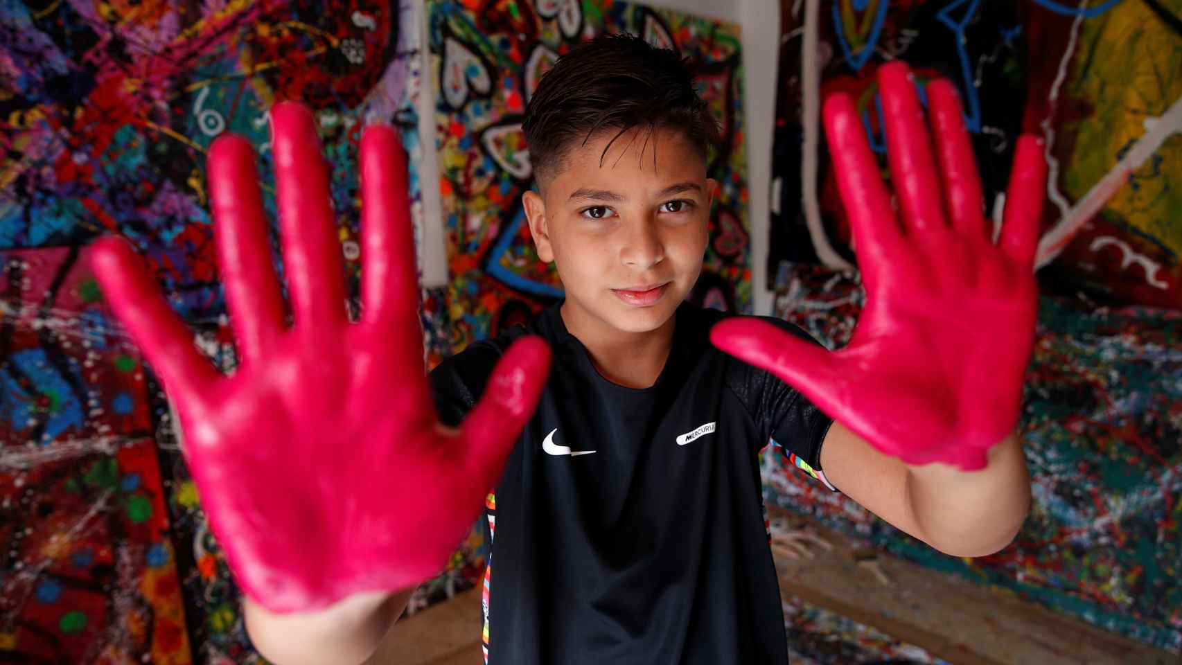 Juanito Cortés, el niño que aspira a ser el pintor más famoso del mundo, en el salón de su casa junto a sus cuadros / EFE - Alejandro García
