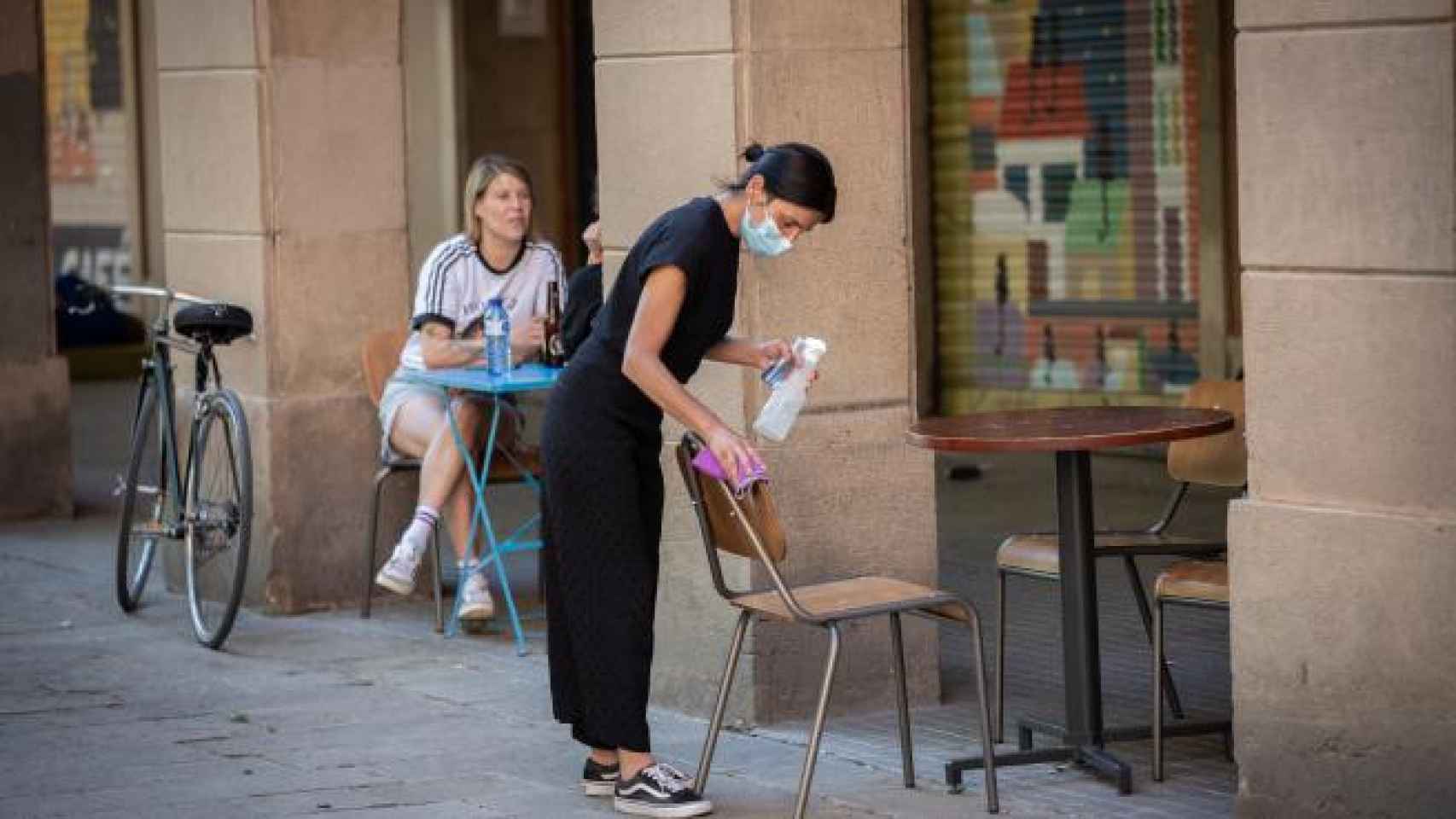 Una trabajadora limpia una mesa en una terraza de Barcelona / EUROPA PRESS - DAVID ZORRAKINO