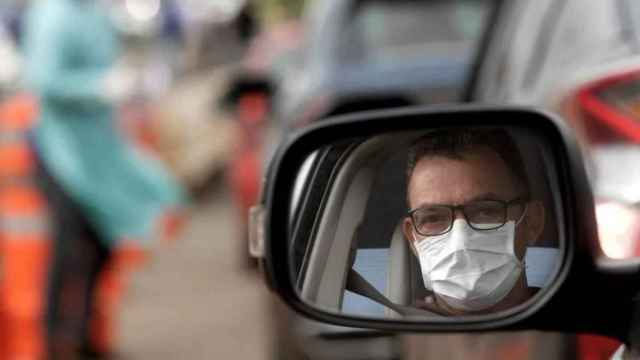 Un hombre con una mascarilla en el interior de un turismo / EFE